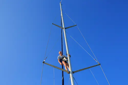 sailor at the top of a yacht mast