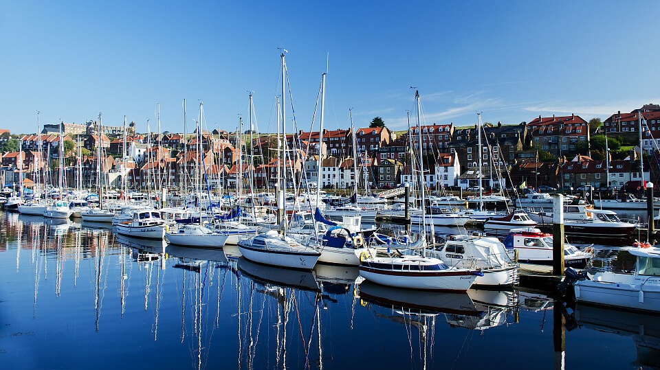 Busy marina with many yachts moored up.